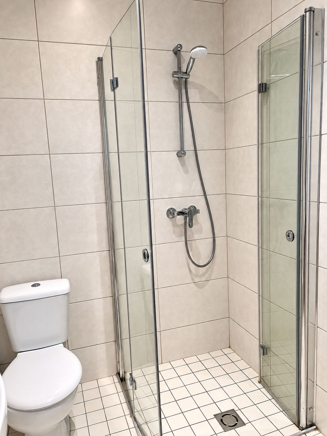 Une salle de bain moderne avec une douche à parois de verre, des toilettes et un revêtement de sol carrelé.