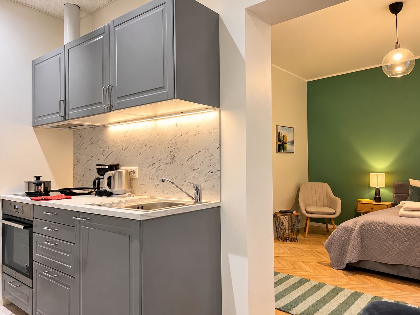 Eine moderne Küche mit grauen Schränken, einer Marmor-Spritzschutzwand und einem eingebauten Backofen.