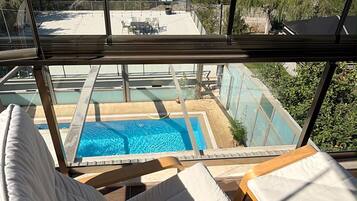 A poolside area with a view of a landscape, including a pool and lounge chairs.