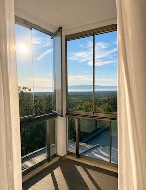 Habitación de esquina con amplios ventanales que ofrecen vistas a un paisaje con árboles y un horizonte lejano.