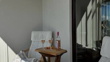A balcony with two chairs, a small table, and a bottle of wine.