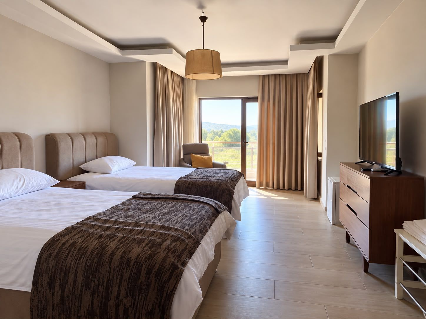 A hotel room with two beds, a television, a dresser, and a view of the outdoors.
