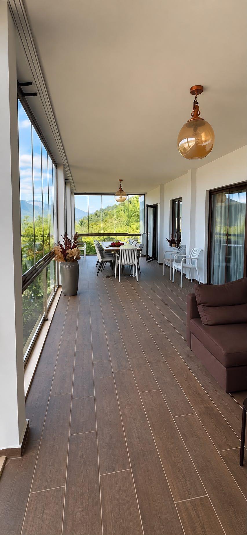 Een ruim balkon met een eethoek, een bank en uitzicht op groen.