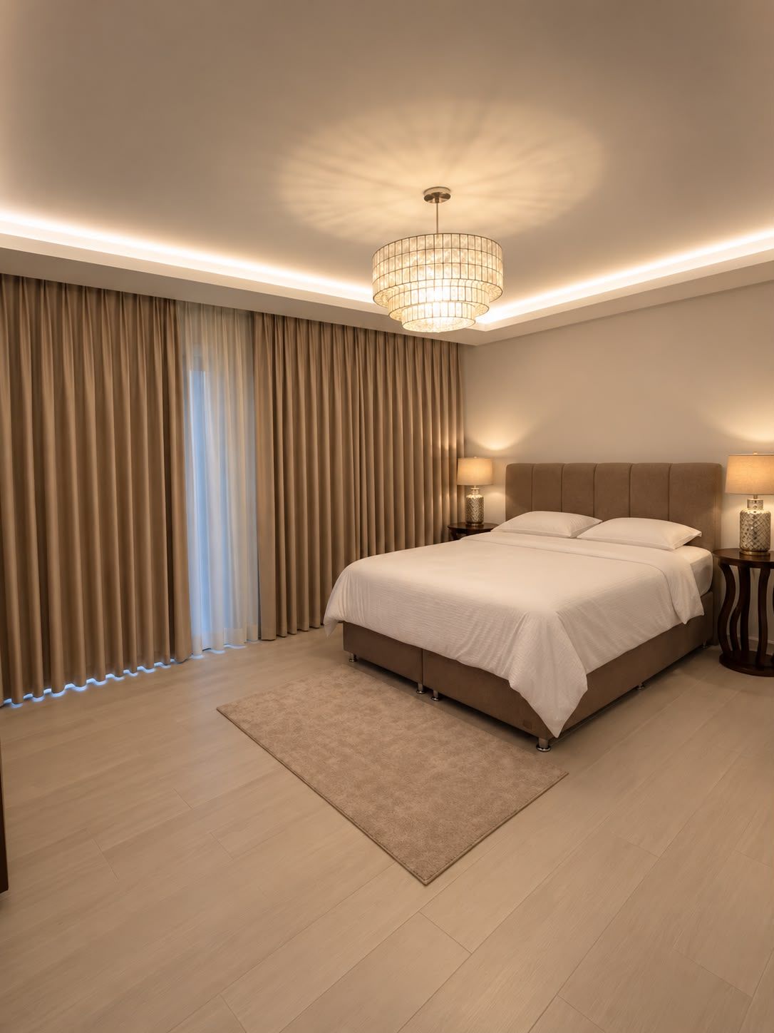 Un dormitorio moderno con una cama grande, una araña y vistas al exterior a través de cortinas.