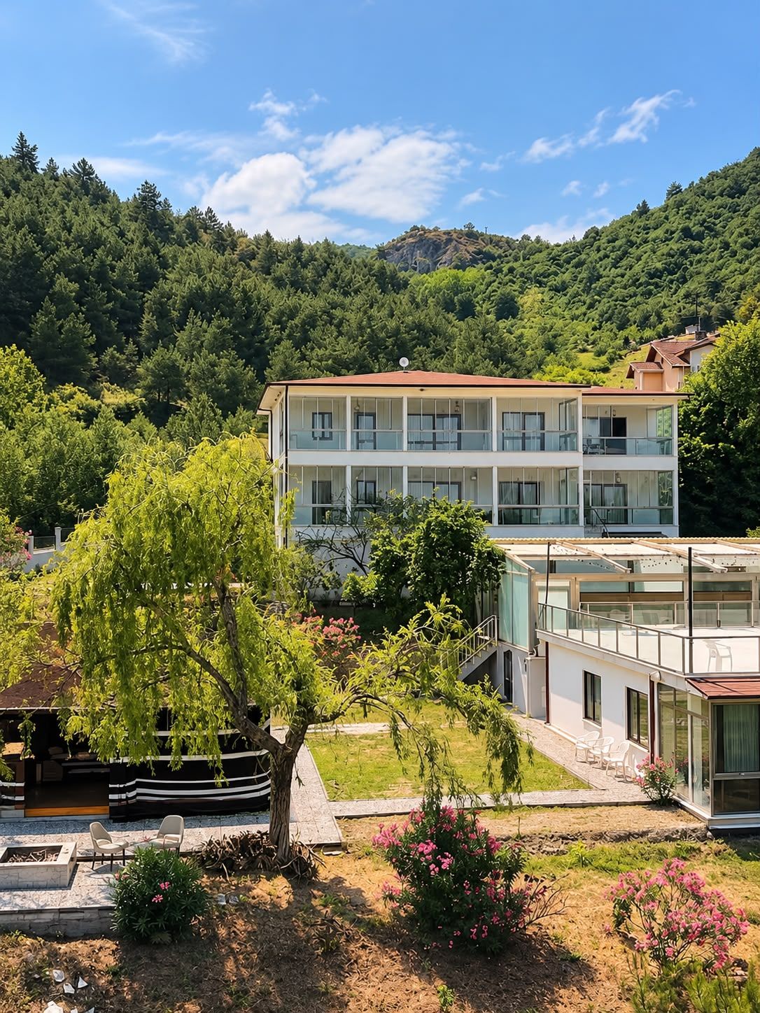 Un edificio de varios pisos con balcones, rodeado de vegetación y colinas.