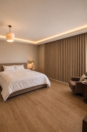 A modern hotel room with a large bed, a bedside table, a lamp, a chair, and a curtain-covered window.