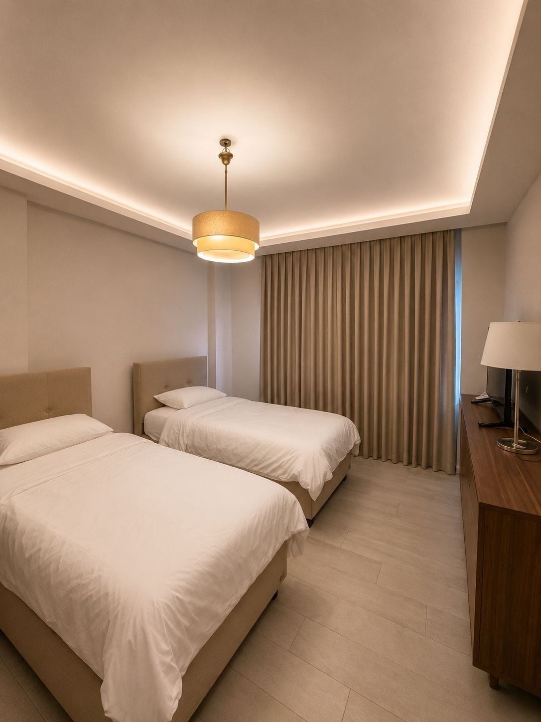 Ein Hotelzimmer mit zwei Betten, einem Schreibtisch, einem Fernseher und einer Deckenleuchte.
