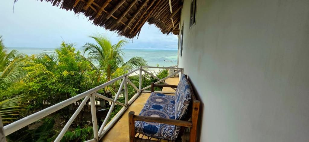 Un balcon avec vue sur l’océan, un toit de chaume et un coussin à motifs.