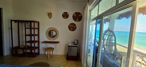Una habitación con estante de madera, una mesita, un espejo y una ventana con vistas al océano.
