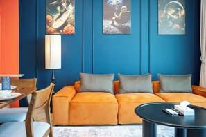 Ein modernes Wohnzimmer mit blauer Akzentwand, einer Couch, einem Couchtisch und Kunstwerken.