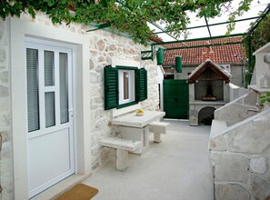 A stone-walled bathroom with a white sink, green shutters, and a green door. - Menego Lodge Bol - Holiday Home With Terrace (Bol)