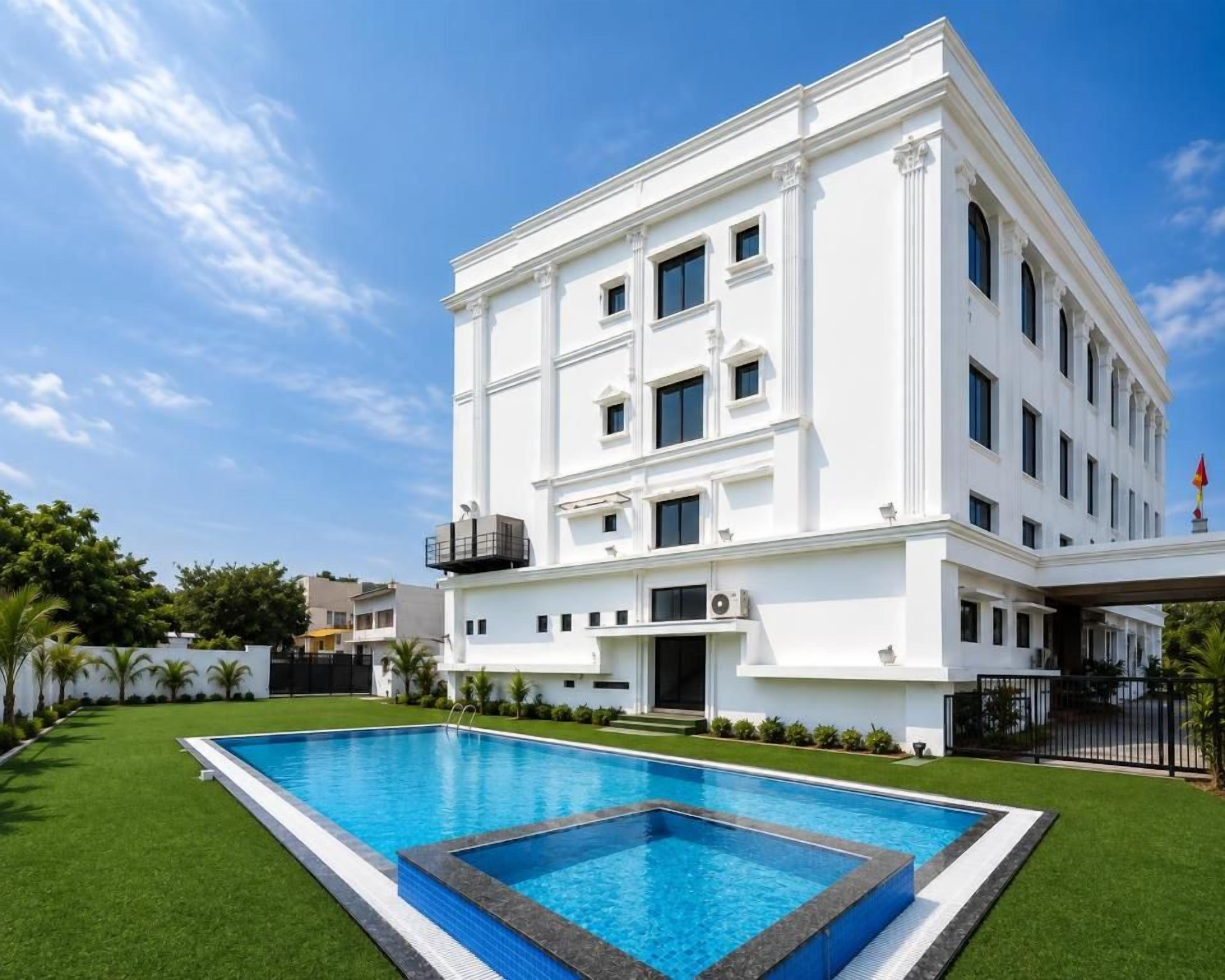 A modern white building with a swimming pool in front.