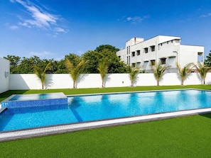 Um edifício moderno com piscina e um gramado bem cuidado.