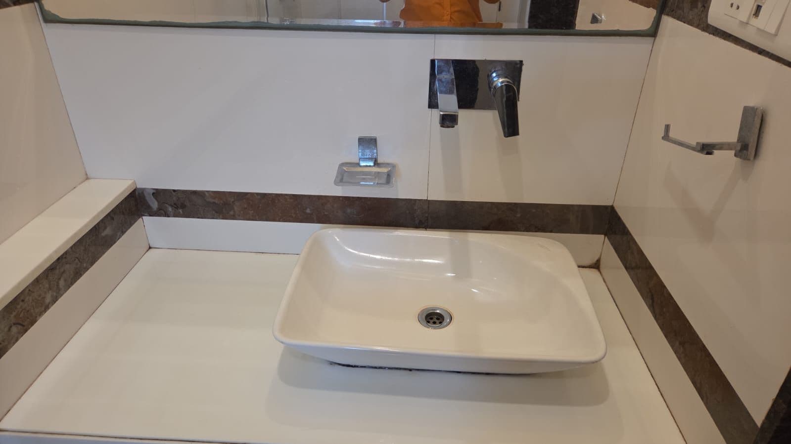 Een badkamer met een witte wasbak, een spiegel en een handdoekhouder.