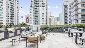 Une terrasse sur le toit, avec des sièges en plein air, un barbecue et une vue sur les immeubles environnants.