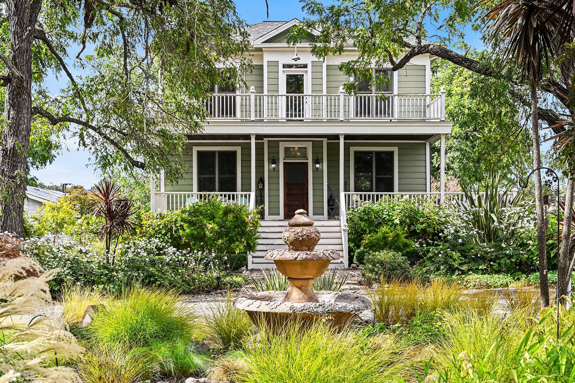 A two-story house with a front porch, a decorative urn, and a well-maintained garden.