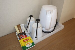 Una cafetera, dos tazas y una caja de té jazmín Tongtong sobre una superficie de madera.