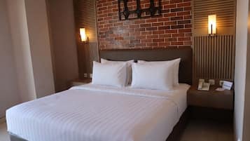 A hotel room with a large bed, a brick wall, and two bedside lamps.