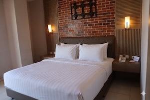 Habitación de hotel con una cama grande, una pared de ladrillo y dos lámparas de noche.
