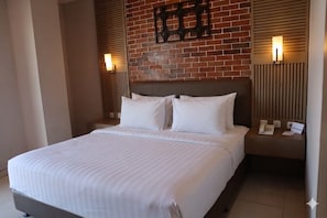 A hotel room with a large bed, a brick wall, and two bedside lamps.