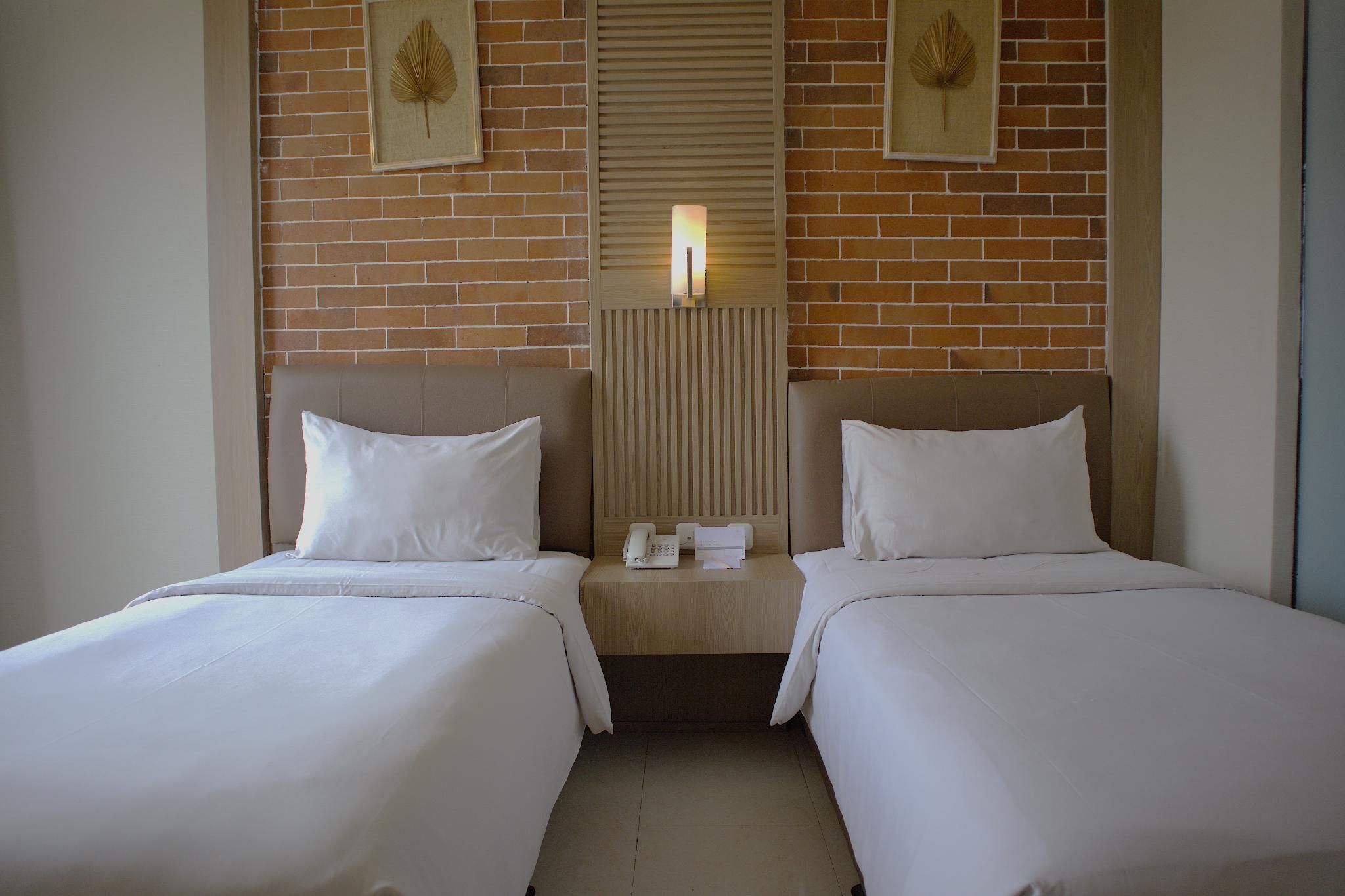 A hotel room with two beds, a wooden headboard, a telephone, and framed wall art.