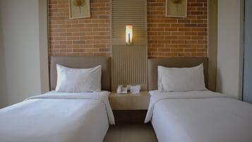 A hotel room with two beds, a wooden headboard, a telephone, and framed wall art.