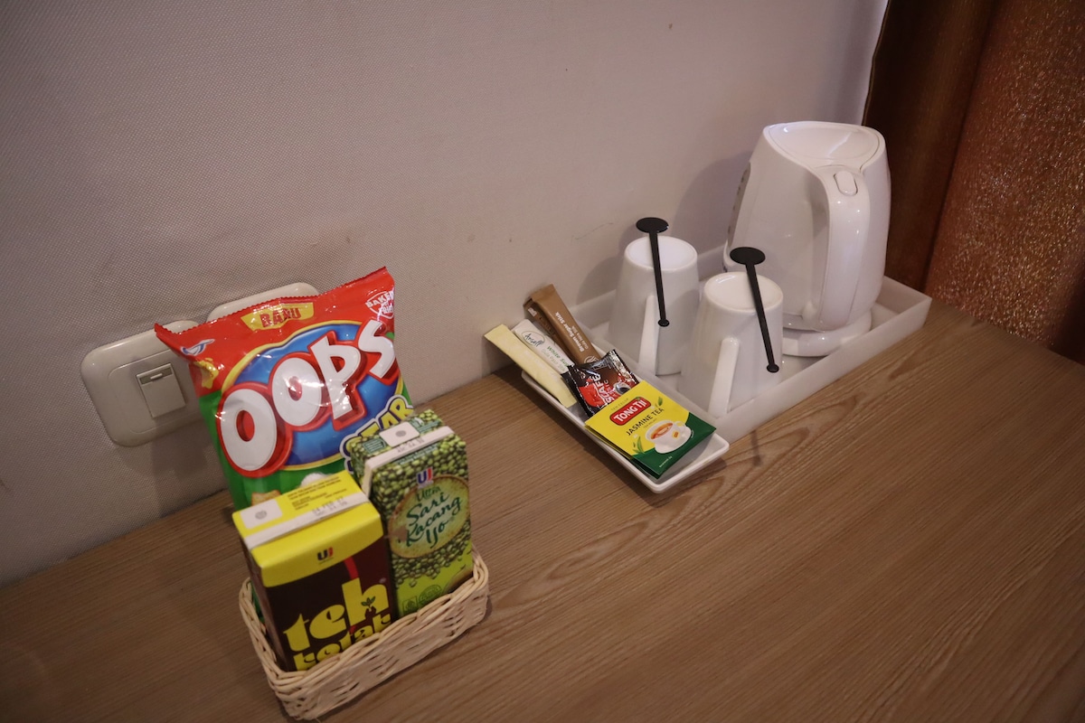 A tray with snacks, a coffee maker, and a tea set on a wooden table.