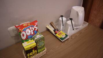 A tray with snacks, a coffee maker, and a tea set on a wooden table.
