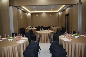 Un salón de conferencias con mesas redondas, sillas, botellas de agua y una pequeña planta en cada mesa.
