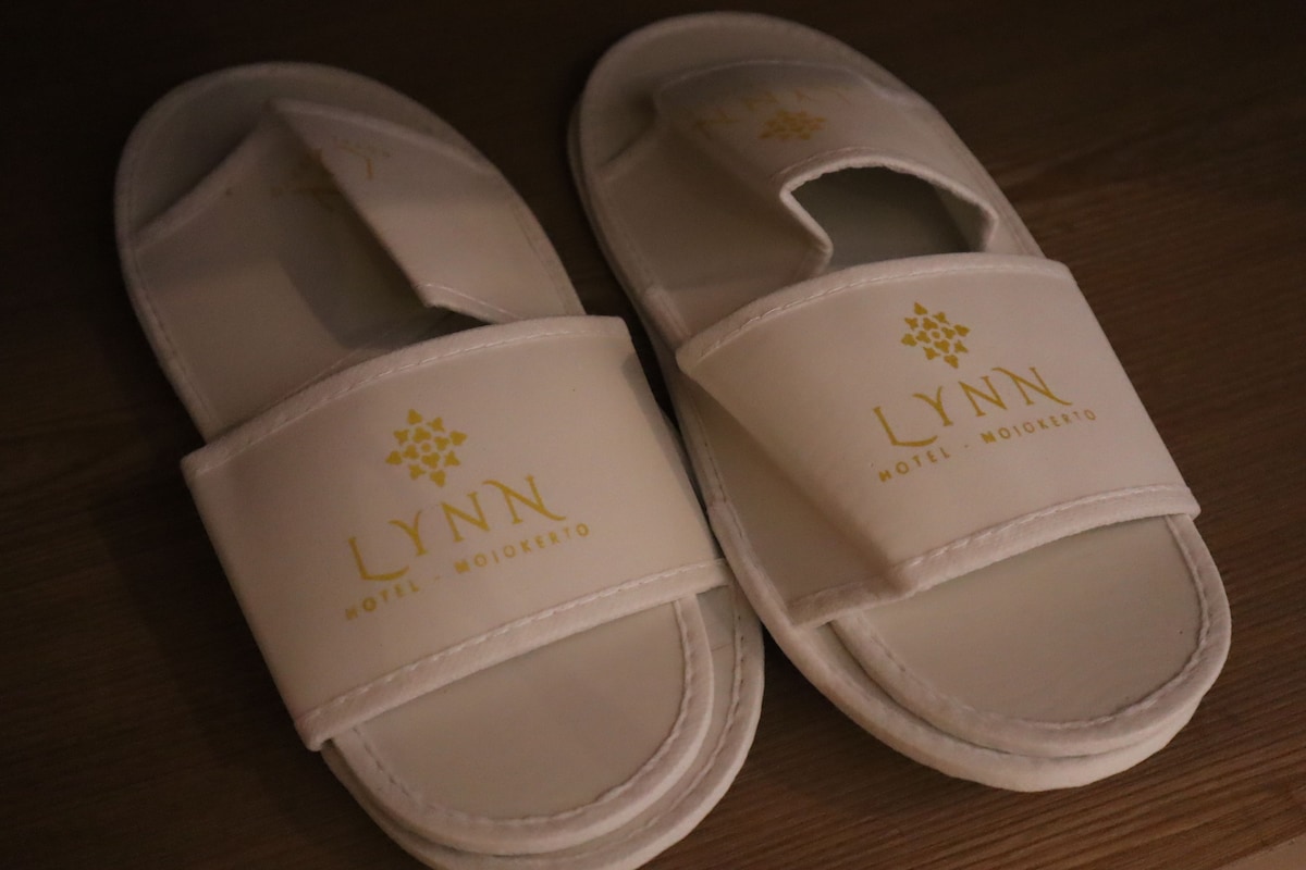 A pair of white slippers with a logo and text indicating they are from a hotel named 'LYNN'.