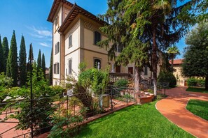 A two-story building with a balcony, surrounded by greenery and a paved pathway. - GuestHost - The Little Tower Between Heaven and Earth (Perugia)