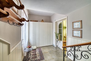 A hallway with a staircase, a white wardrobe, a small table with a rug, and a plant. - GuestHost - The Little Tower Between Heaven and Earth (Perugia)