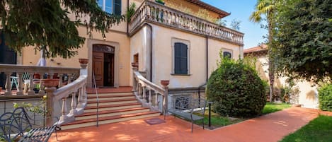 A building with a staircase leading to a door, a bench, and a potted plant.