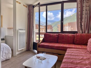 A room with a large window, a sofa, a table with glasses, and a bed. - (BO.130) Family-friendly two-bedroom apartment with a view of the slopes, Les Menuires (Les Menuires)