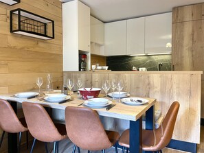 A modern dining area with a wooden table set for four, surrounded by chairs. - (VM.308) 4-room PREMIUM - Alpine Style - (Les Menuires)