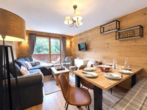 A cozy room with a sofa, a dining table set for two, and a television mounted on the wall. - (VM.308) 4-room PREMIUM - Alpine Style - (Les Menuires)