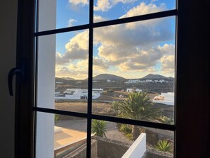Ein Fenster mit Blick auf eine Landschaft, inklusive Gebäude und Berge.