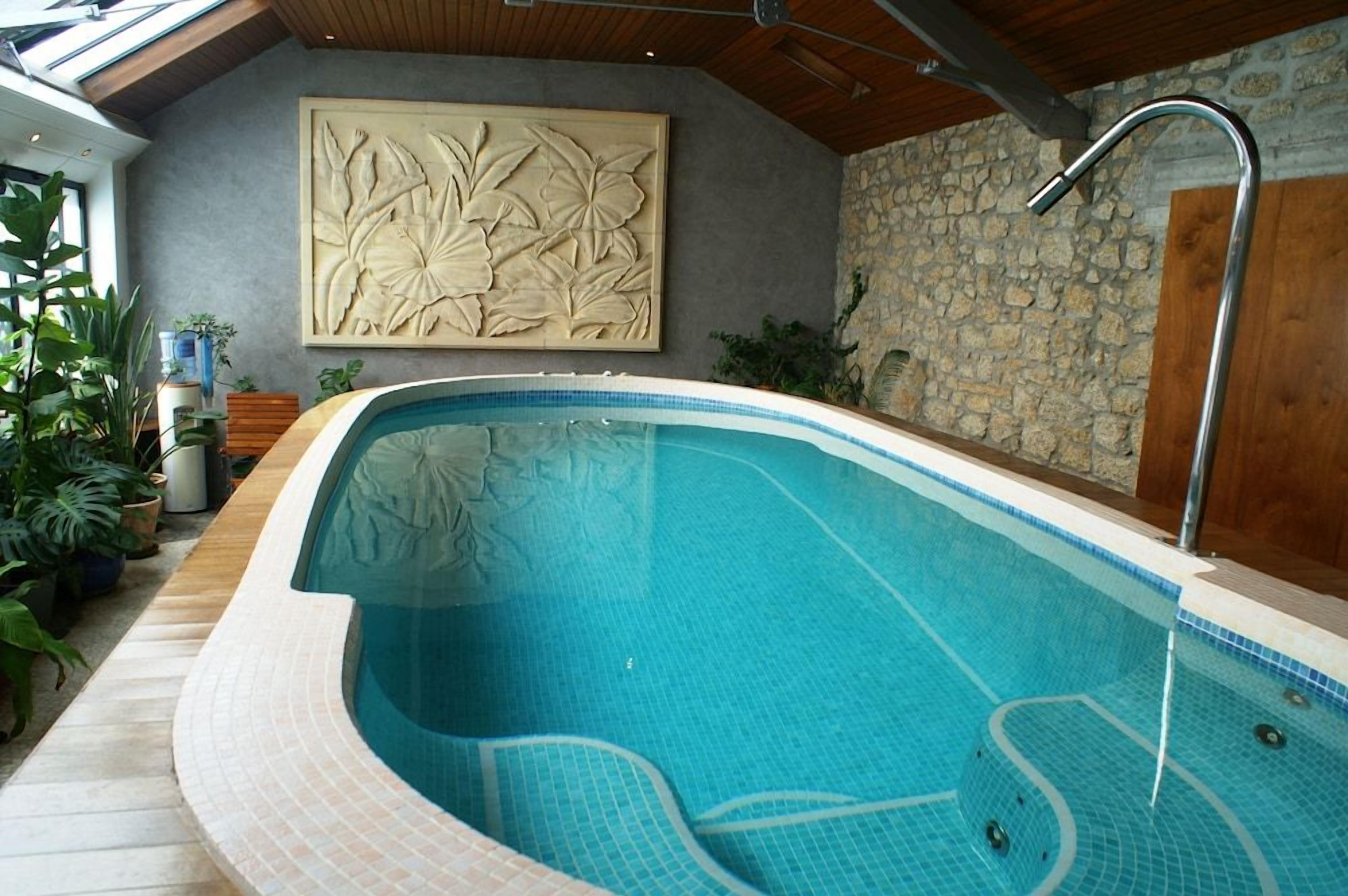 An indoor swimming pool with a stone wall and a wooden ceiling.