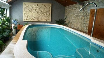 An indoor swimming pool with a stone wall and a wooden ceiling.