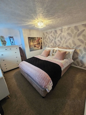 Ein Schlafzimmer mit einem Bett, einem Schminktisch, einer Wandlampe und einem Poster.