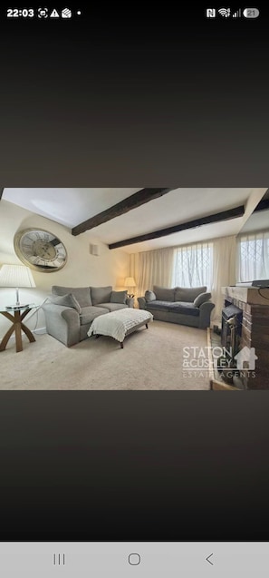 Ein Wohnzimmer mit zwei Sofas, einer Uhr und einer Lampe.
