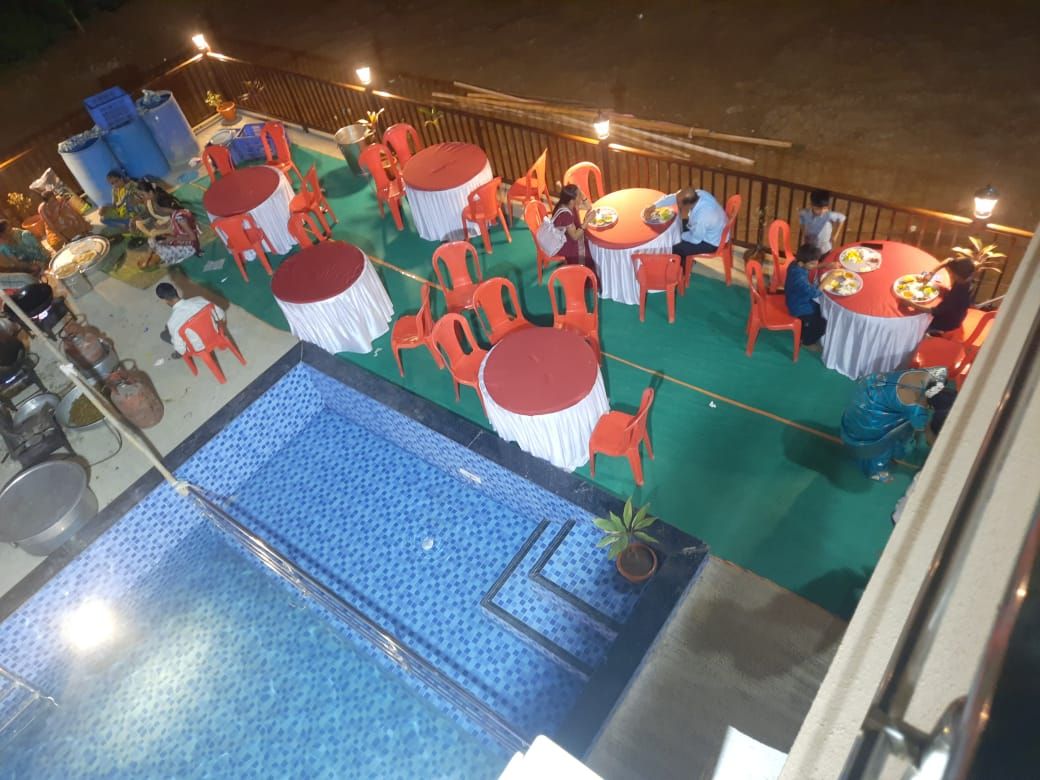 An outdoor dining area with round tables and chairs, a pool, and a wooden fence.