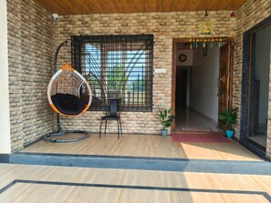 Fachada de ladrillo con una silla colgante, una planta en maceta y una puerta de acceso.