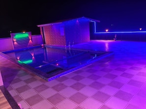 Un espace piscine sur le toit, doté d’une structure en verre et d’un petit bâtiment en briques.