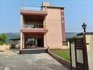 Un edificio de dos pisos con balcón, un portón y vistas del paisaje.