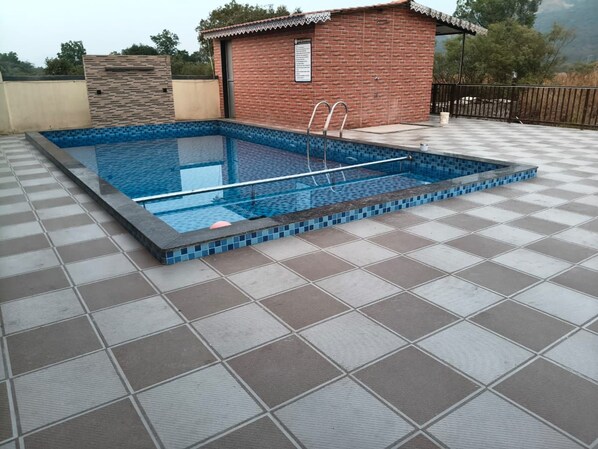 Una piscina rectangular con borde de azulejos y escaleras metálicas a los lados.