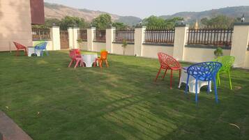 A well-maintained lawn with outdoor seating and a view of a hill.