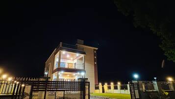 A multi-story building with a gated entrance, illuminated by exterior lights.