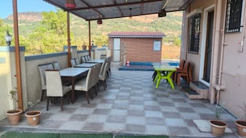 Eine Außenpatio mit überdachter Sitzgruppe, einem kleinen Backsteinhaus und Topfpflanzen.