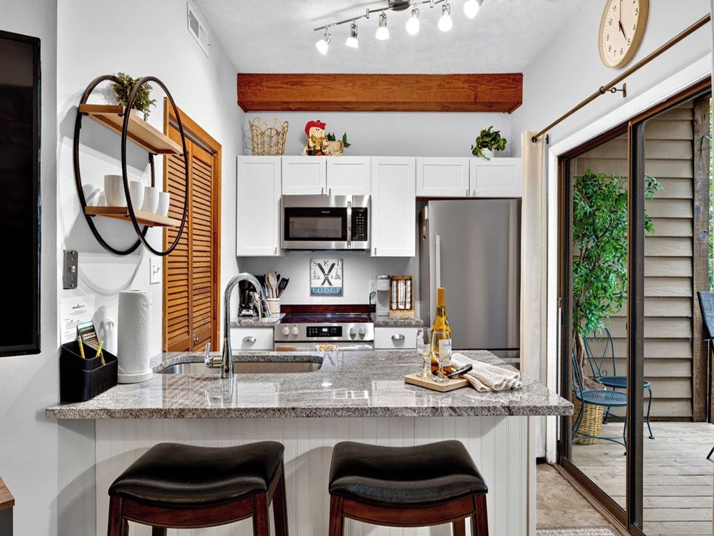 A modern kitchen with white cabinets, stainless steel appliances, and a central island with bar stools.